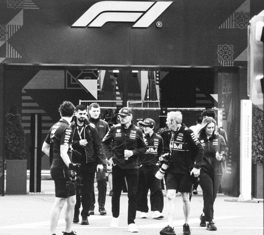 Formula 1 team members walk past the f1 logo